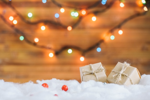 Caixas de presentes na neve decorativa perto de luzes de fadas Foto gratuita